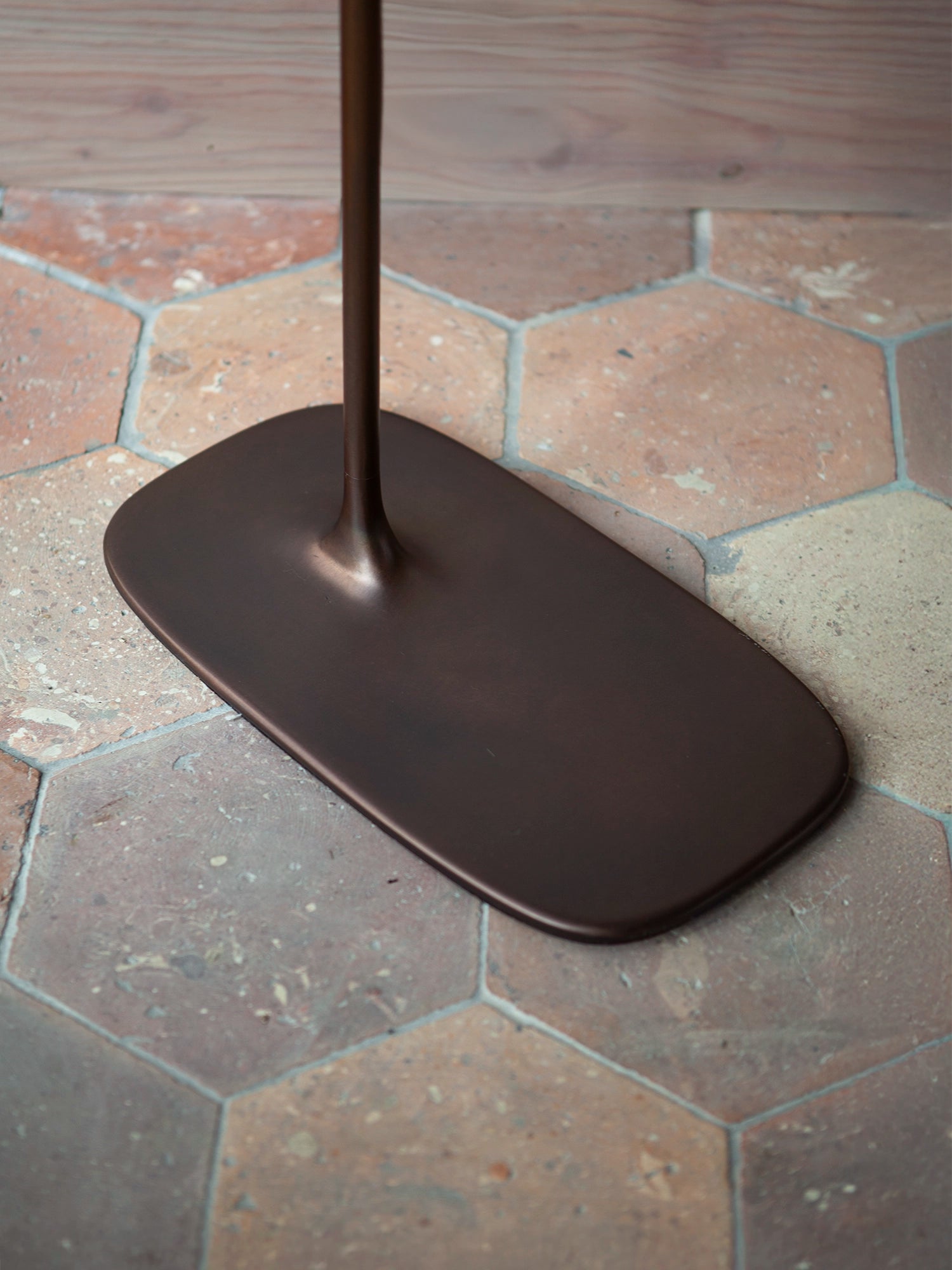 Heavy, solid brass base of the low Fluid table, providing a grounded architectural presence.