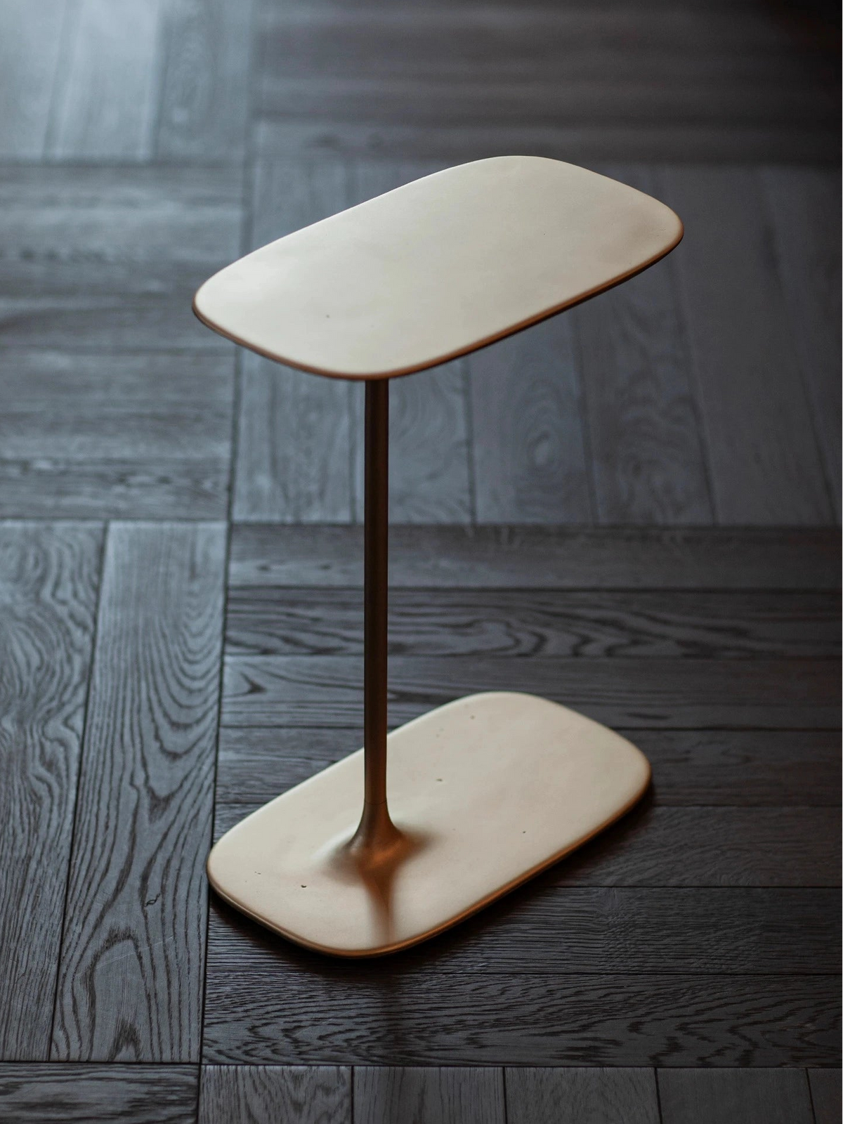 Precise vertical lines meeting the fluid base in a brushed brass finish, balancing art and craft.