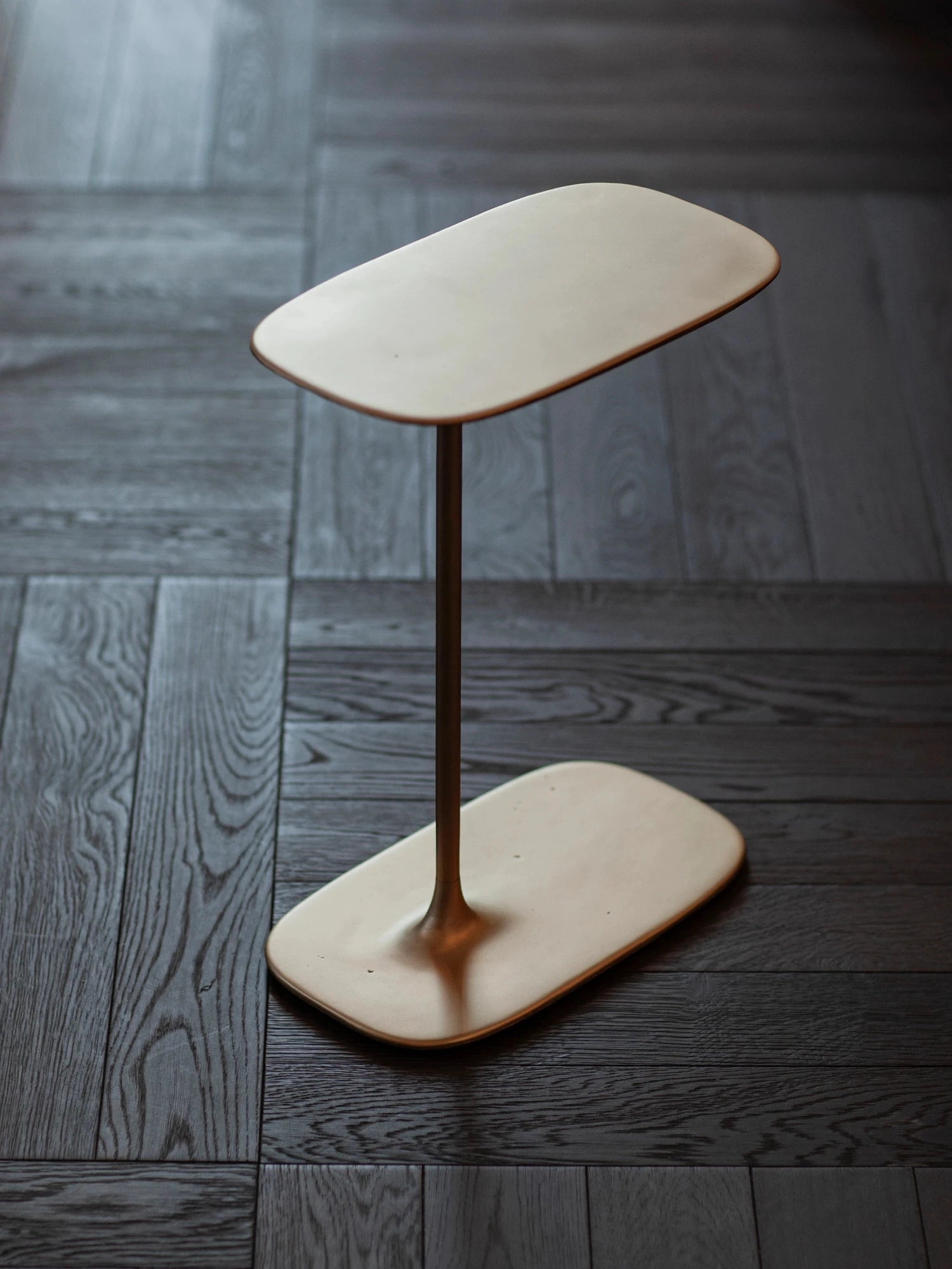Precise vertical lines meeting the fluid base in a brushed brass finish, balancing art and craft.