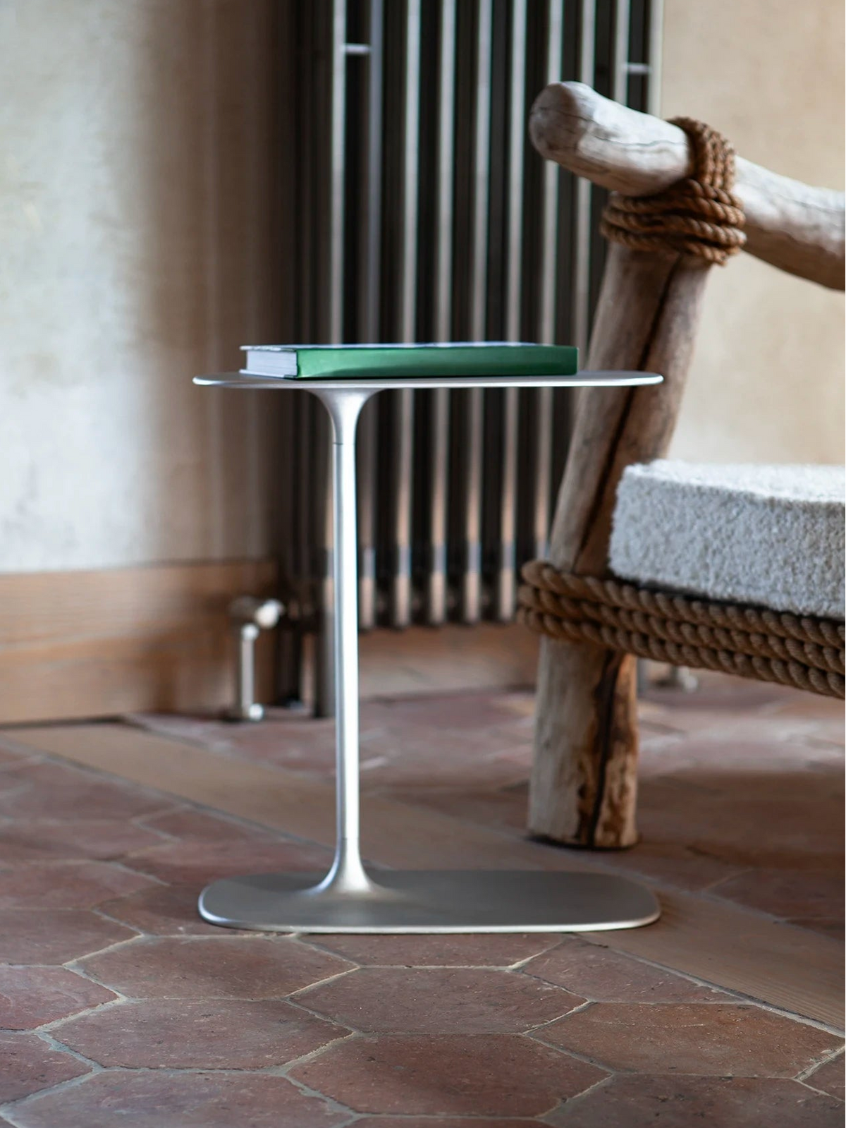 The sculptural, fluid leg of the brushed aluminium table, capturing soft ambient light.