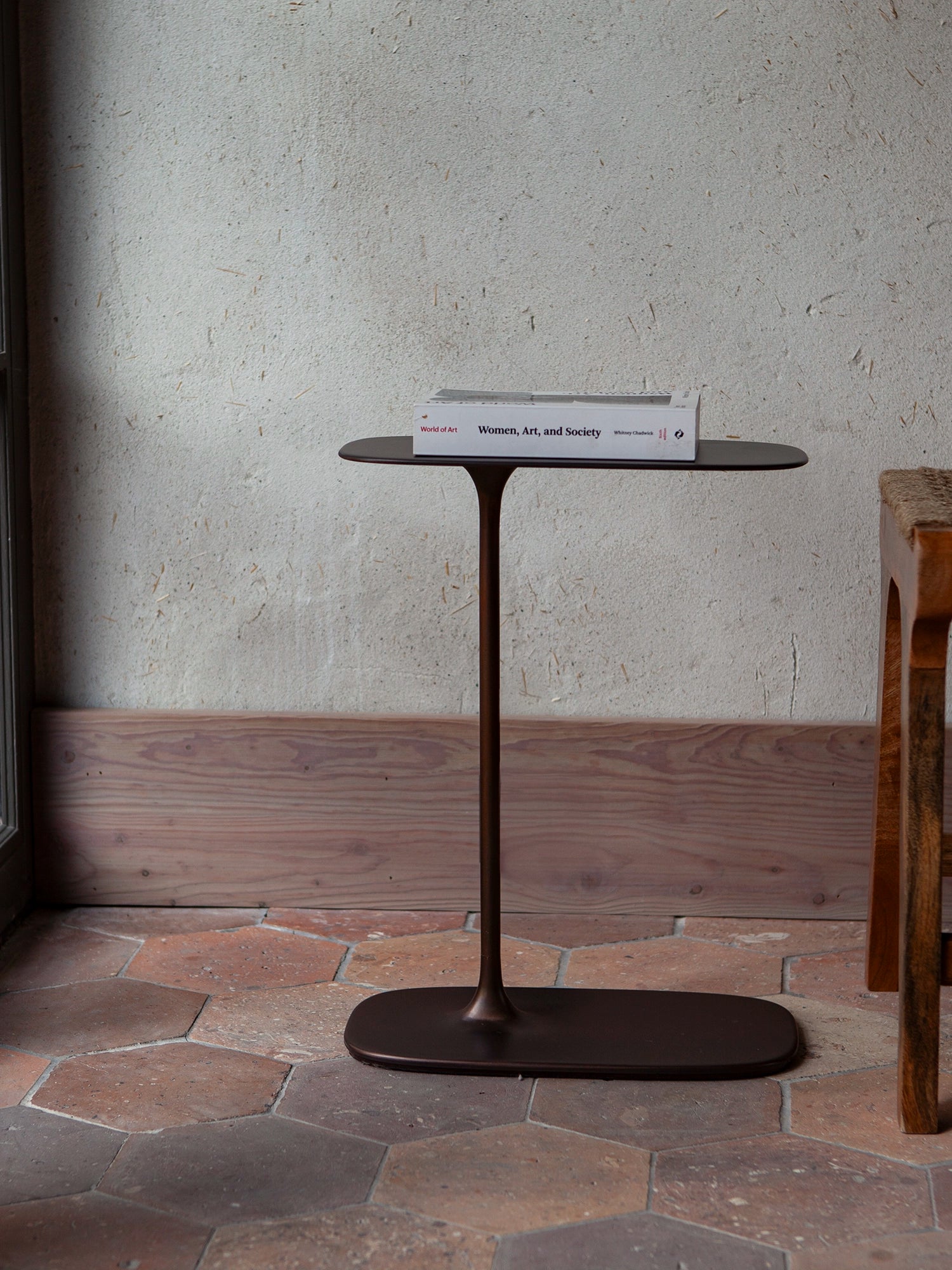 The 'molten' aesthetic of the aged brass low table, showcasing its unique sand-molded geometry. Heavy book sitting on top.